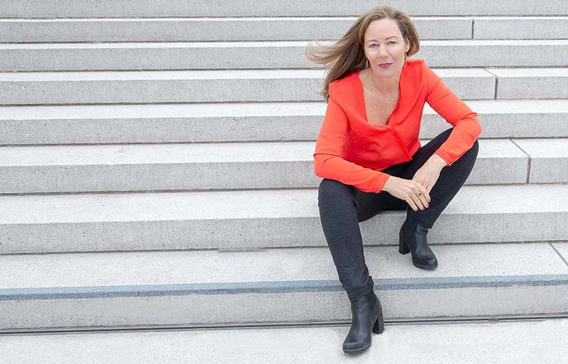 Außenaufnahme, Frau sitz an der Treppe, Fontalblick, Farbfoto in Querformat.